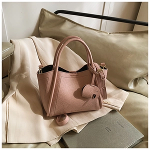 Close-up of pink litchi grain leather bucket bag with a cute elephant pendant detail