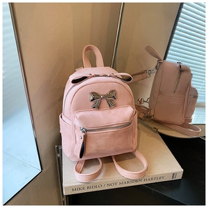Gros plan du mini sac à dos rose en velours avec détail de nœud en métal argenté