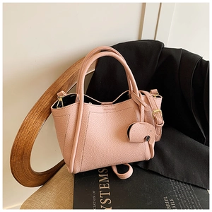 Macro detail of lychee grain pink bucket bag with a cute elephant charm on a chair