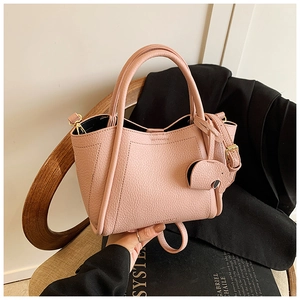 Pink litchi texture leather bucket bag with cute elephant pendant on vintage chair