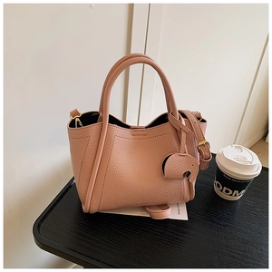 Detail of light pink pebble leather bucket bag featuring a cute elephant charm and gold hardware