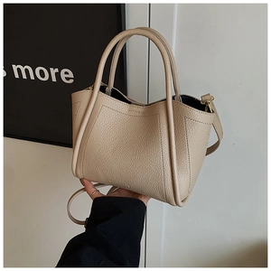 Detail of beige lychee texture leather bucket bag with top handles and logo