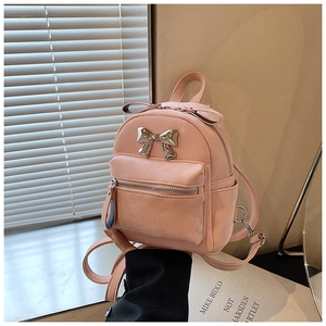 Vue détaillée du mini sac à dos rose avec nœud en métal argenté et texture délicate