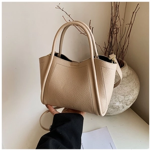 Close-up of beige lychee texture bucket bag with cylindrical handle and slim strap