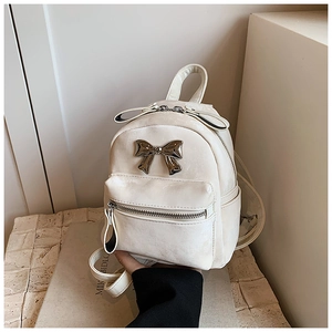 Détail d'un mini sac à dos blanc avec nœud en métal argenté et texture de cuir poli