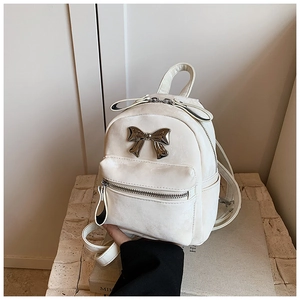 Détail d'un mini sac à dos blanc crème avec nœud métallique et finition en similicuir lisse