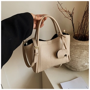 Detail view of cream bucket bag with lychee texture leather and gold buckle hardware