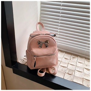 Vue détaillée du mini sac à dos en cuir rose avec un nœud en métal argenté