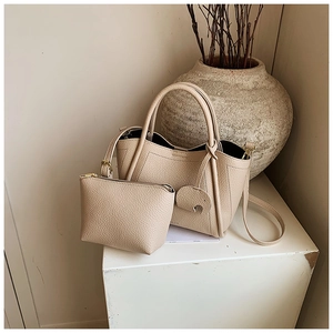 Detail view of beige lychee texture bucket bag with a small pouch and leather charm