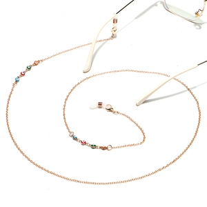 Handmade gold chain glasses strap featuring colorful enamel evil eye charms on white background