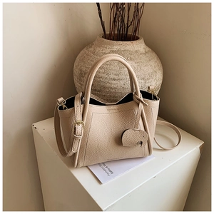 Detailed macro of beige lychee leather bucket bag with cute elephant charm and gold hardware