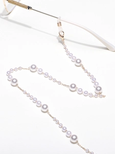 Detail of gradient pearls eyewear chain with gold lobster clasp on white glasses