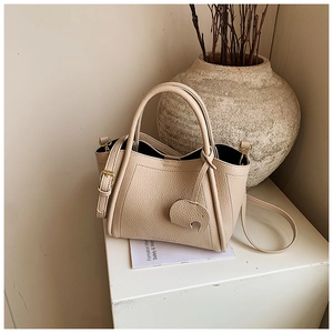 Detail of beige lychee leather bucket bag with cute elephant charm and adjustable strap