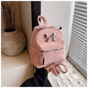 Détail d'un mini sac à dos rose avec un nœud en métal argenté et une texture en cuir