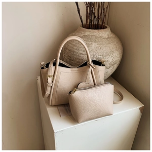 Detail of lychee pattern bucket bag set with matching pouch on minimalist stone base