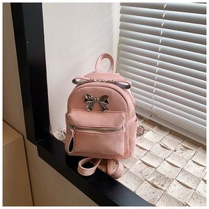 Détail d'un mini sac à dos en similicuir rose avec un nœud décoratif en métal argenté