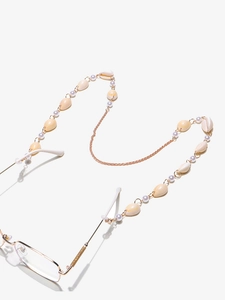 Détail de la chaîne de lunettes dorée ornée de coquillages et de perles blanches
