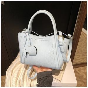 Close-up of light blue pebble leather tote bag with gold hardware and elephant charm