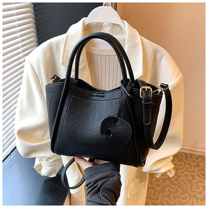 Close-up of black lychee grain leather bucket bag with cute elephant charm and strap