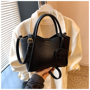 Close-up of black litchi grain leather bucket bag with cute elephant pendant charm