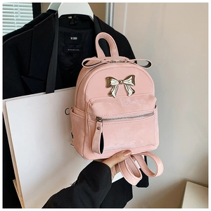 Détail d'un mini sac à dos en velours rose avec nœud métallique et fermeture éclair