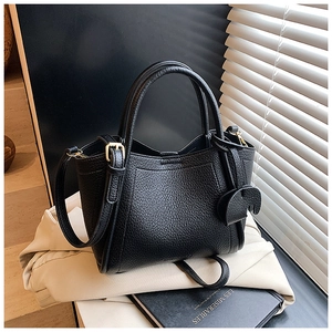 Detail of black lychee grain leather handbag with cute elephant charm and gold hardware