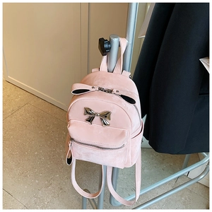 Détail du mini sac à dos rose avec texture velours et décoration noeud métallique