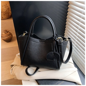 Close-up of black pebble leather bucket bag with gold hardware and elephant charm detail