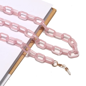 Détail de la chaîne à lunettes en acrylique rose avec maillons et fermoirs dorés