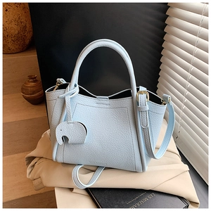 Detail of light blue lychee leather bucket bag with cute elephant charm and gold hardware