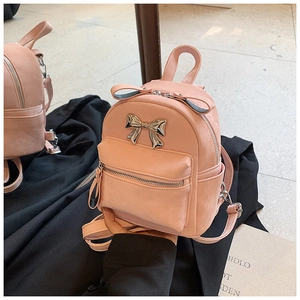 Détail du mini sac à dos rose avec noeud en métal doré et finition en cuir PU texturé