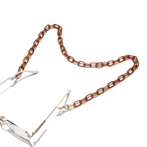 Détail d'une chaîne de lunettes en acrylique ambré avec fermoirs dorés fins