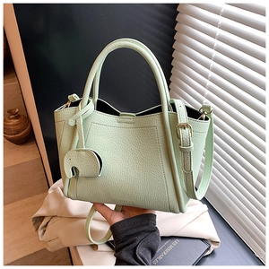 Detail of mint green lychee pattern leather bucket bag with cute elephant charm and strap