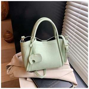 Detail view of mint green pebble leather bucket bag with cute elephant charm and strap