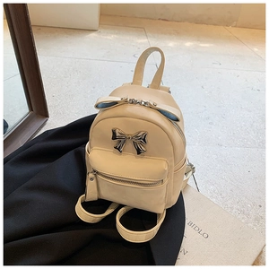 Détail d'un mini sac à dos crème avec nœud en métal argenté et poche zippée à l'avant