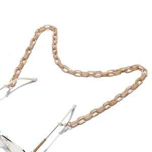 Détail de la chaîne à maillons en acrylique marbré beige avec anneaux dorés et boucles en gomme