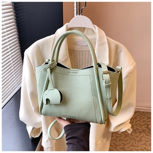 Detail of mint green tote bag with lychee texture and elephant charm accessory