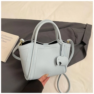 Detail of light blue lychee pattern bucket bag with elephant charm on grey blazer