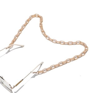 Détail de la chaîne de lunettes en acrylique crème avec clips dorés et boucles en silicone