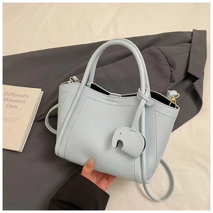 Detail of light blue pebble leather bucket bag with cute elephant charm and thin strap