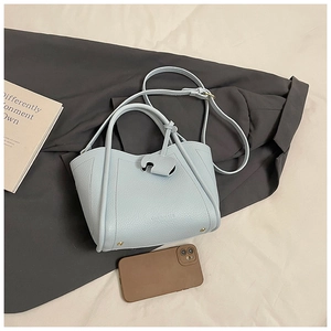 Detail of light blue pebble leather bucket bag with cute elephant charm and gold studs