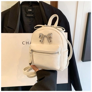 Gros plan d'un mini sac à dos en cuir PU blanc avec nœud en argent et poche zippée