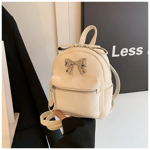 Gros plan d'un mini sac à dos en cuir crème avec nœud en argent et fermeture éclair
