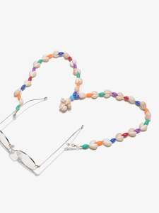 Detail of colorful beads and natural shells heart-shaped eyewear chain on gold glasses