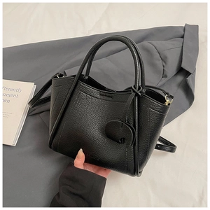 Close-up of black lychee texture bucket bag with heart pendant and leather dual handles