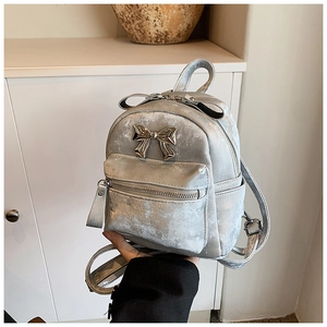 Détail d'un mini sac à dos argenté avec un nœud en métal et une texture cuir craquelé