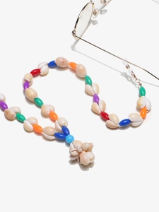 Close-up of handmade seashell eyewear chain with colorful beads and gold metal clips