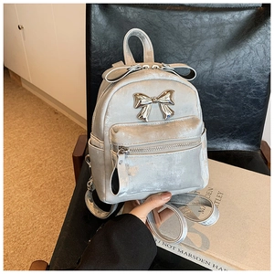 Gros plan sur un mini sac à dos gris argenté orné de nœuds décoratifs et texture velours