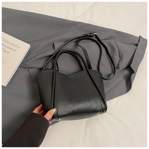 Detail view of black lychee grain leather handbag with bottom protective gold studs