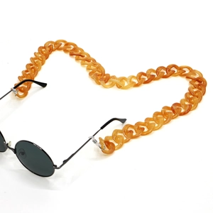 Detailed macro view of amber acrylic glasses chain with thick textured links on white background